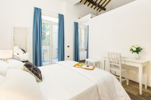 a white bedroom with two beds and a desk at Residenza le Scalette in Cagliari