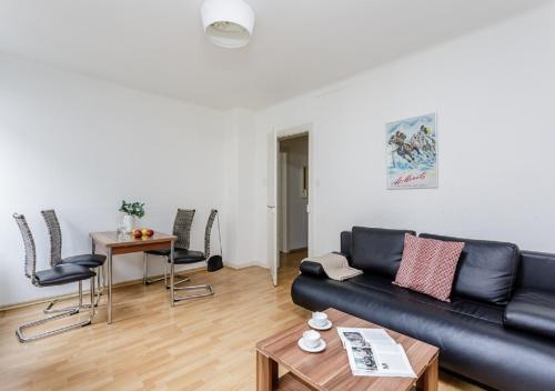 ein Wohnzimmer mit einem schwarzen Ledersofa und Stühlen in der Unterkunft Rent a Home Eptingerstrasse - Self Check-In in Basel