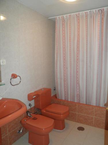 La salle de bains est pourvue de toilettes rouges et d'un lavabo. dans l'établissement Apartamento Casa Geli #1, à La Robellada de Onis