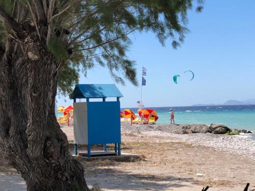 a blue trash can on a beach next to a tree at Retas apartment up in Kremasti