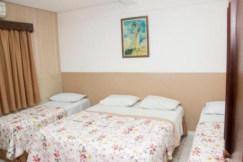 a room with two beds and a painting on the wall at Hotel Morada do Mar in Guarujá