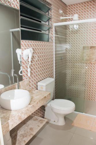 a bathroom with a toilet and a sink and a shower at Hotel Morada do Mar in Guarujá