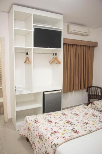 a bedroom with a bed and a tv and shelves at Hotel Morada do Mar in Guarujá
