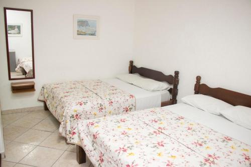 a bedroom with two beds and a mirror at Hotel Morada do Mar in Guarujá