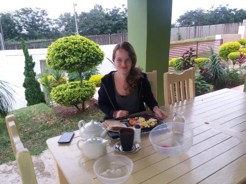 een vrouw aan een tafel met een dienblad met eten bij Mkhumbane Backpackers in Durban