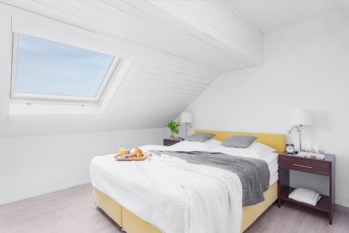 a white bedroom with a large bed with a window at Swiss Star Marc Aurel - Self Check-In in Zurich