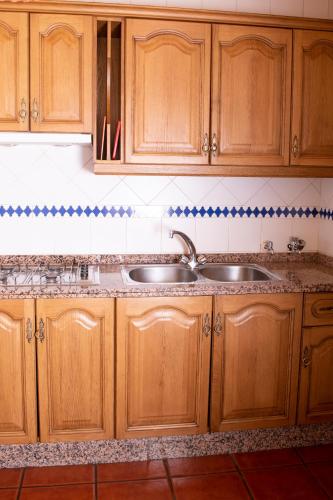 a kitchen with wooden cabinets and a sink at Apartamentos Vista Veleta in Capileira