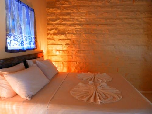 a bed with two pillows and a window on it at Pousada Pedras de Igatu in Igatu
