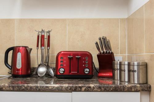 a red toaster sitting on a kitchen counter with utensils at Bazpackers in Inverness