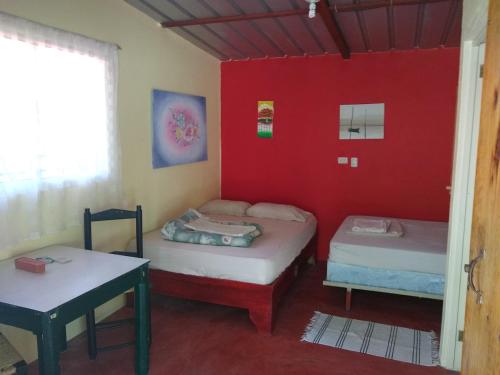 two beds in a room with a red wall at Conrado's Guesthouse B&B in Las Avispas