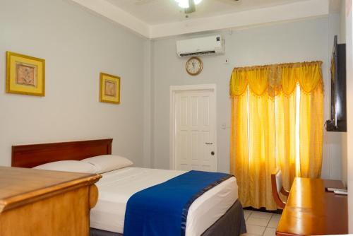 a bedroom with two beds and a clock on the wall at Status International Hotel in Georgetown