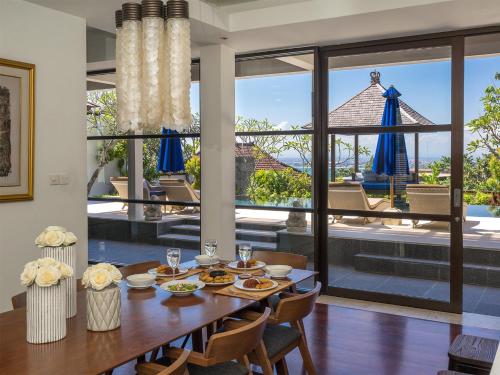 een eetkamer met een tafel en uitzicht op een patio bij Villa Adenium by Elite Havens in Jimbaran