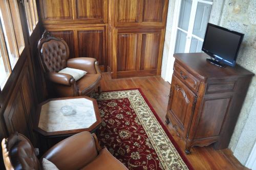 a living room with a tv and a chair and a table at Casa Manuel Espregueira e Oliveira in Viana do Castelo