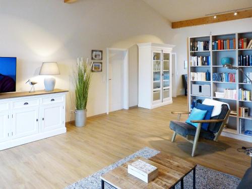 a living room with a couch and a chair and book shelves at Weiße Düne Ferienwohnung *Weiße Düne 7* in Wittdün