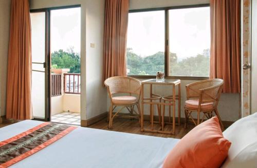 1 dormitorio con 1 cama, mesa y sillas en Takiab Beach Resort en Hua Hin