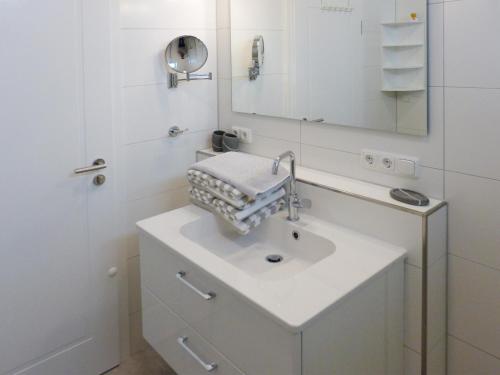 a white bathroom with a sink and a mirror at Weiße Düne Ferienwohnung *Weiße Düne 7* in Wittdün