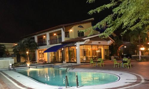 a swimming pool in front of a house at night at Porto Bello Hotel Boutique in Puerto Colombia