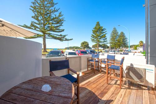 a patio with chairs and a table on a deck at Pavilion Beachfront Apartments in Mount Maunganui