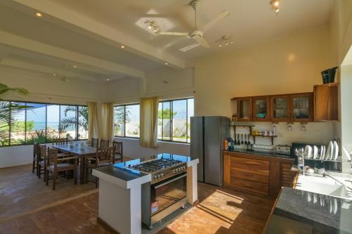 a large kitchen with a stove and a dining room at The Palm Residence by Amazing Zanzibar in Chanjani