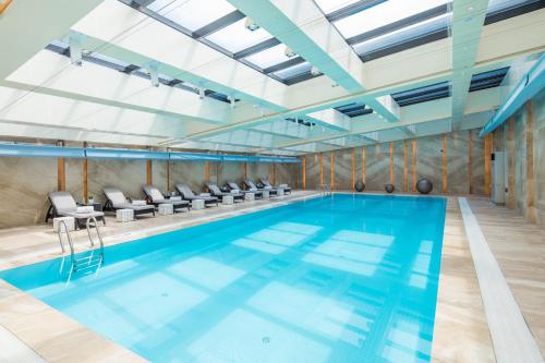 a large indoor swimming pool with blue water at Golden Tulip Shanghai Hongqiao - A Louvre Hotel in Shanghai