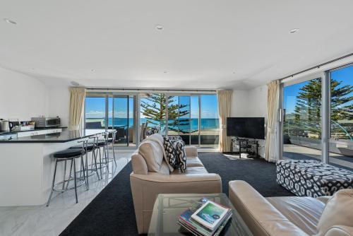 ein Wohnzimmer mit einem Sofa und einer Bar mit Aussicht in der Unterkunft Pavilion Beachfront Apartments in Mount Maunganui