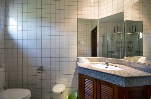 a bathroom with a sink and a mirror and a toilet at Family-friendly house, a few steps from the pool and close to the ocean. in Mae Pim