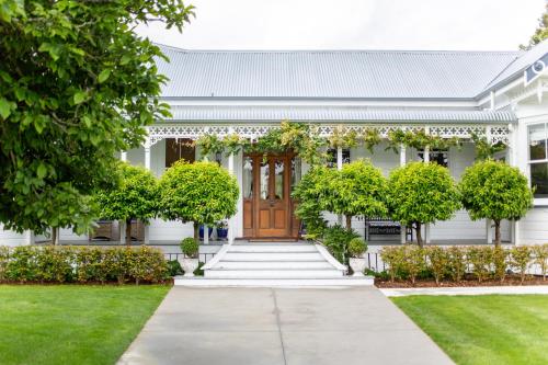 a white house with a wooden door and trees at Villa Walton in Matamata