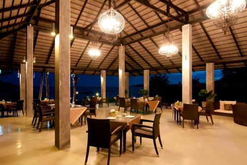 a restaurant with tables and chairs and chandeliers at Plub Pla Koh Mak Retreat in Ko Mak