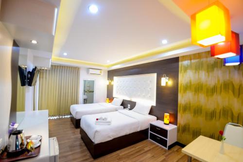 a hotel room with two beds and a desk at โรงแรมลลิตา บูติค in Hat Yai