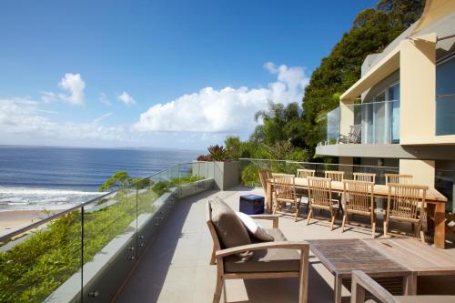 Un balcón con mesa y sillas y el mar. en Hastings Park: Luxury Penthouse, Private Pool & Views, en Noosa Heads