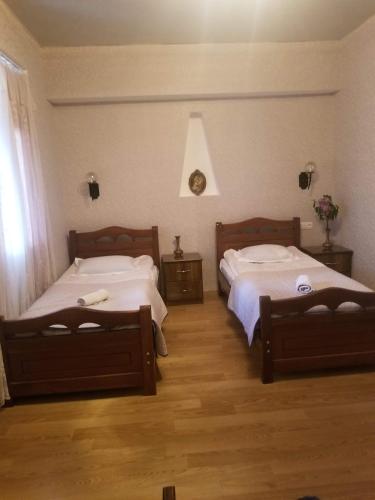 two beds in a room with wooden floors at Guest House Shvelidze in Borjomi