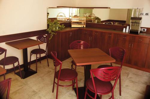 un restaurante con mesas de madera y sillas rojas en La Corte Albergo Meublé, en Bagnolo San Vito