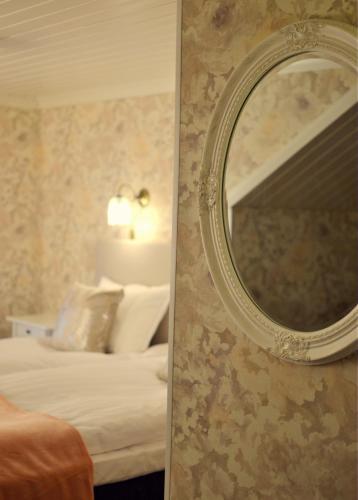 a mirror on a wall next to a bedroom at Putiikkihotelli Kemi 1932 in Kemi