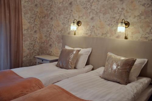 two beds in a hotel room with lamps on the wall at Putiikkihotelli Kemi 1932 in Kemi