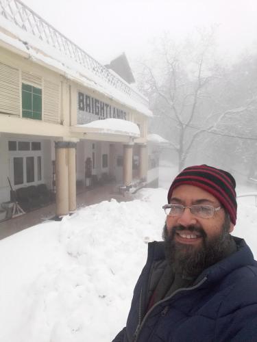 a man standing in front of a building in the snow at BRIGHTLANDS HOTEL in Murree