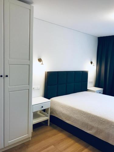 a bedroom with a white bed and a blue headboard at Taikos apartamentai Nidoje in Nida