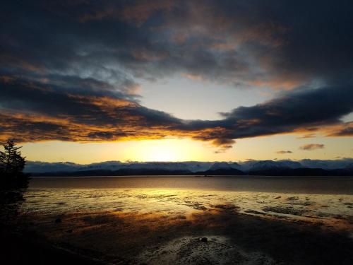 a sunset over a body of water with a cloudy sky at The Lighthouse in Homer
