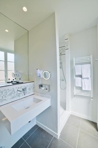 une salle de bain blanche avec un lavabo et un miroir dans l'établissement Hôtel Mercure Bayonne Centre Le Grand Hotel, à Bayonne