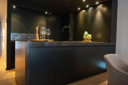 a kitchen with a sink and a counter with wine glasses at LombokLodge Apartment Knokke in Knokke-Heist