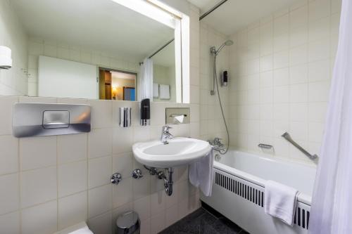 ein Badezimmer mit einem Waschbecken, einem Spiegel und einer Badewanne in der Unterkunft Trip Inn Bristol Hotel Mainz in Mainz