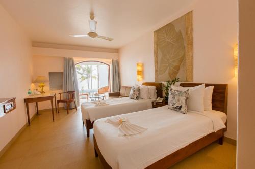Cette chambre comprend 2 lits et une table. dans l'établissement Prainha Resort By The Sea, à Panaji