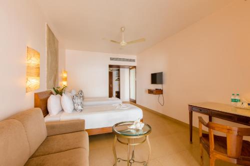 a bedroom with a bed and a couch and a table at Prainha Resort By The Sea in Panaji