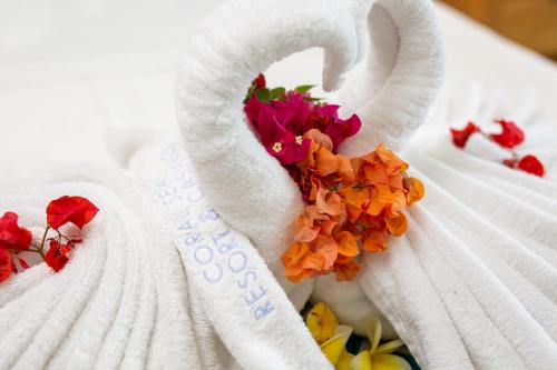uma toalha branca com flores numa cama em Coral Sea Resort & Casino em Honiara