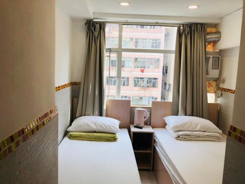 two beds in a room with a window at Chung Kiu Come Inn in Hong Kong