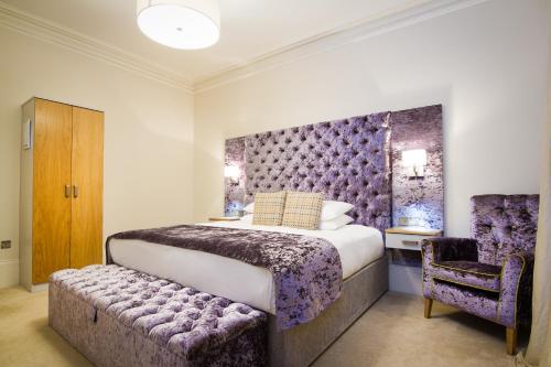a bedroom with a king sized bed and a chair at White Hart Hotel & Apartments in Harrogate
