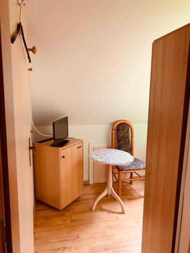 a room with a table and a television and a chair at Pension Stürrad in Neuharlingersiel