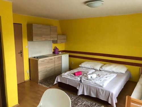 żółty pokój z łóżkiem i kuchnią w obiekcie Apartmány Ingrid w Beszeniowej