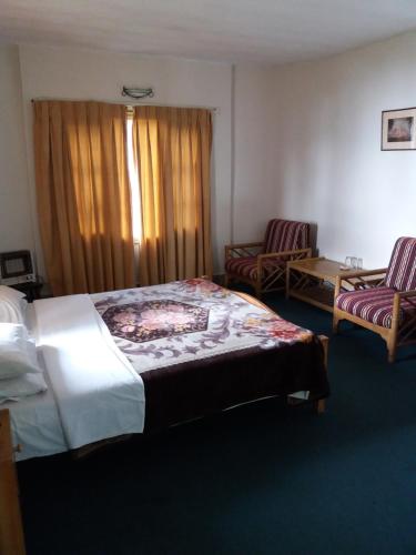 a hotel room with a bed and two chairs at BRIGHTLANDS HOTEL in Murree