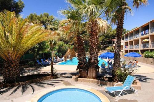 une vue sur la piscine du complexe avec des palmiers dans l'établissement Sanary sur Mer Appartement 30m2 T2 avec terrasse Piscine 10min à pied de la plage, à Sanary-sur-Mer