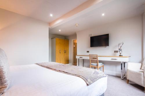 a bedroom with a bed and a desk and a tv at White Hart Hotel & Apartments in Harrogate